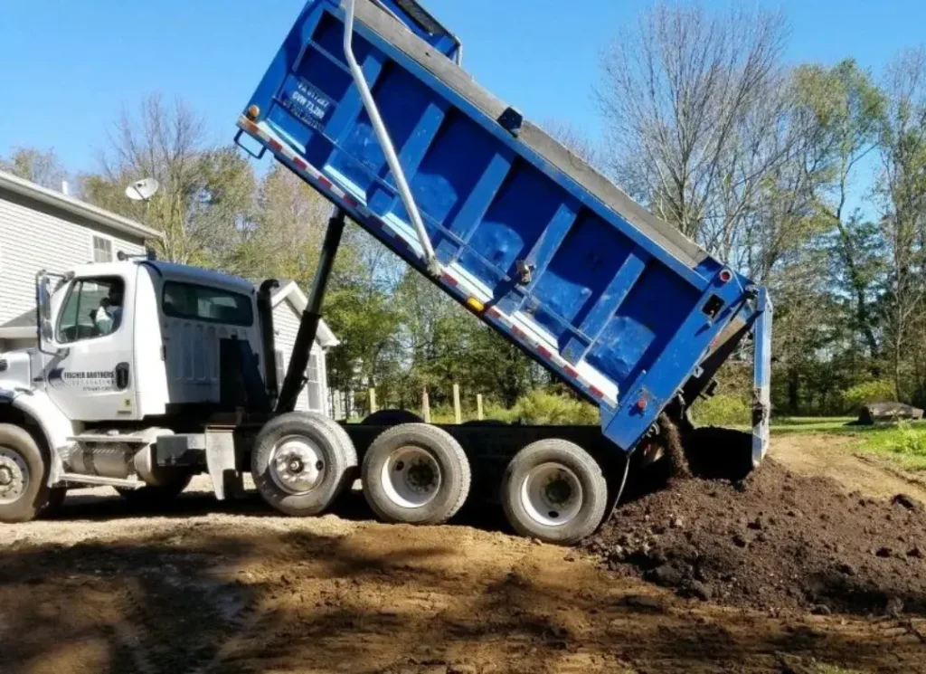 Blue dump truck dumping gravel.